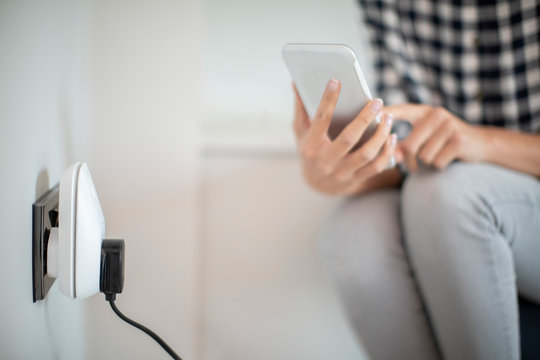 Woman Controlling Smart Plug Using App On Mobile Phone