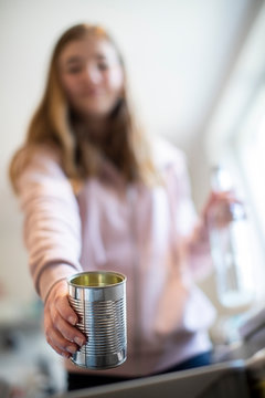 Teenage Girl Sorting Recycling Into Kitchen Bin At Home