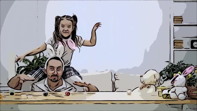 Happy and cheerful daughter is sitting on her father's shoulders and dancing. Father is sitting under the wooden table, where there are a few colorful paints. Father is moving in a time with his