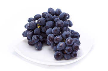 Blue grapes on a white plate.