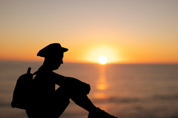 silhouette of a backpacker man sitting at sunset