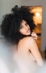Young charming naked black woman in room
