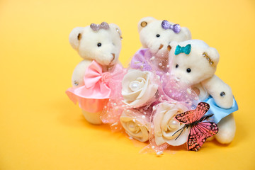 Obraz premium Teddy bears with roses and butterfly on yellow background. Toys