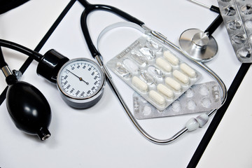 phonendoscope and tonometer  with a folder with white sheets of paper and pills  on a white background