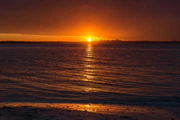 Bright orange red sunset sky over water