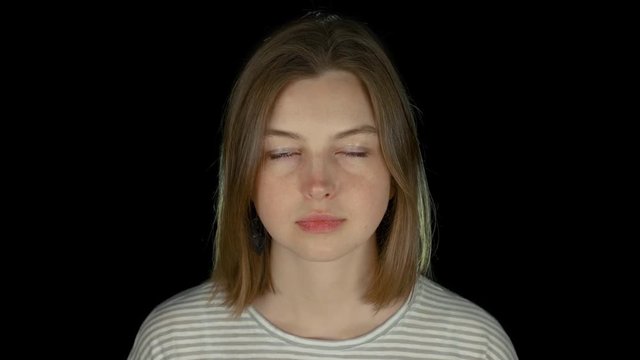 Close-up portrait of young serious long-haired caucasian girl in black studio