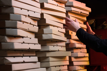 Close up of stacks with pizza boxes in low neon yellow light