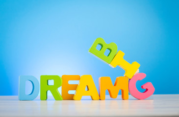 Business success concept, DREAM BIG  word on wooden desk over blue background