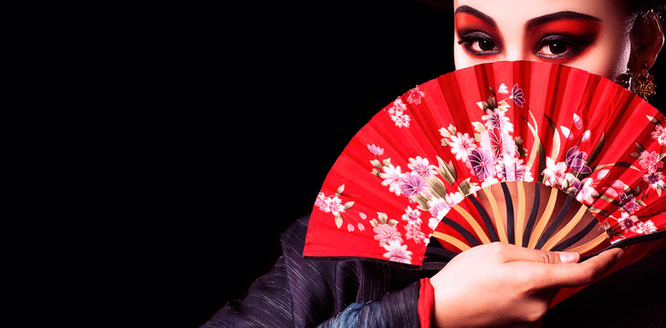 beautiful Japanese girl in kimono with a fan on a black background