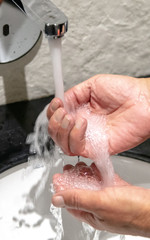 A man washes his hands under the tap