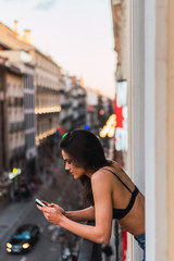 Young woman in lingerie with smartphone on balcony