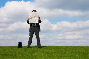Caucasian businessman reading a map in a field