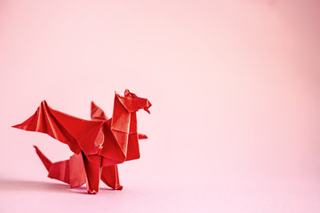 Origami dragon in red on a plain background.  Paper Origami. Сopy space - obrazy, fototapety, plakaty