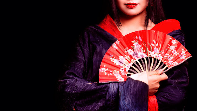beautiful Japanese girl in kimono with a fan on a black background