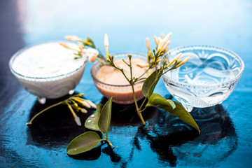 Obraz na płótnie Canvas Ayurevidic face pack of Indian jasmine in a glass bowl on wooden surface i.e. jasmine Petals well mixed with milk cream & water. Used for skin whitening purposes.
