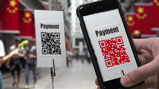 Scanning QR CODE look alike pattern (CAN NOT SCAN THIS) to make a cashless payment via smart phone.  Blurred street in China background.