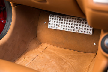 Close up of chrome leg rest in brown car interior