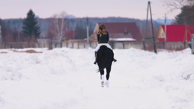 Winter time. A woman riding a horse in a village