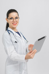 Portrait of brunet in doctors costume with a modern tablet in her hands isolated on background