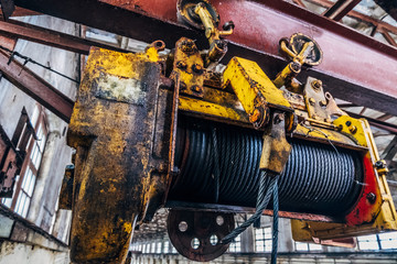 Old rusty hoist of Industrial overhead crane in factory. Close up