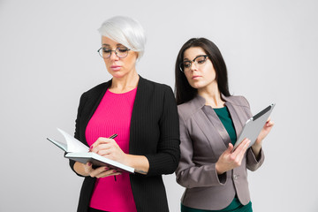 Portrait of two young buisness ladies in costumes isolated on background