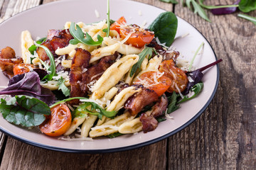 Handmade fusilli pasta with pancetta, roasted cherry tomatoes and fresh green vegetables