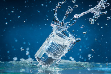 falling small glasses and spilling water on a blue background