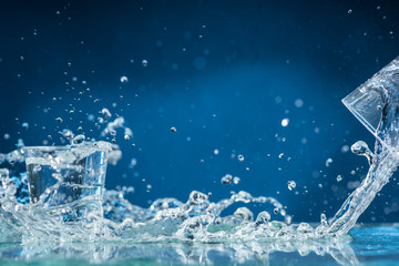falling small glasses and spilling water on a blue background