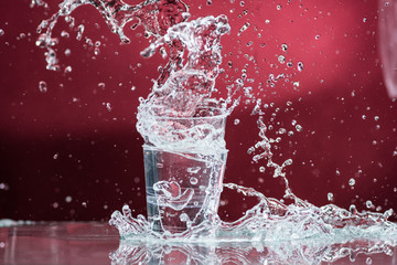 falling small glasses and spilling water on a red background