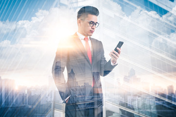 Fototapeta premium The double exposure image of the businessman using a smartphone during sunrise overlay with cityscape image. The concept of modern life, business, city life and internet of things.