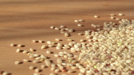 Slow dolly movement from right to left. Brown rice on a wooden table. Close up. Raw rice out of the paper bag.