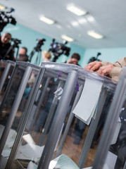 Illustrative image of the election in a democratic society. Elections in Ukraine. The process of voting at a polling station. The voter throws the ballots in the ballot box.