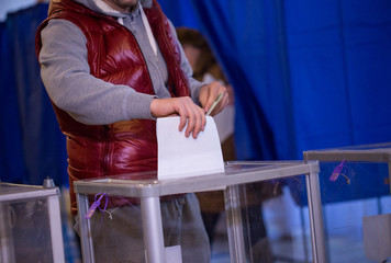 Illustrative image of the election in a democratic society. Elections in Ukraine. The process of voting at a polling station. The voter throws the ballots in the ballot box.