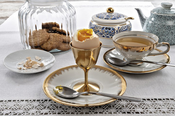 uovo bollito sgusciato rotto con biscotti e tazza di the