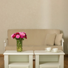 Beige sofa with pillows in the living room and vase with Flowers (Michaelmas daisy, asters).