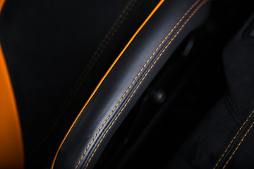 Orange contrast stitching on black leather car seat