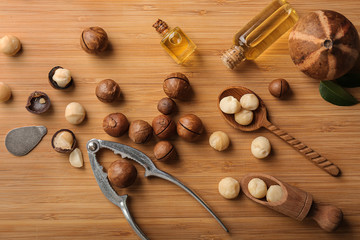 Macadamia nuts with nutcracker and oil on wooden background