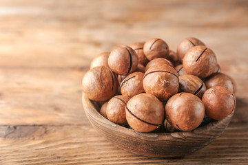 Plate with tasty macadamia nuts on wooden table