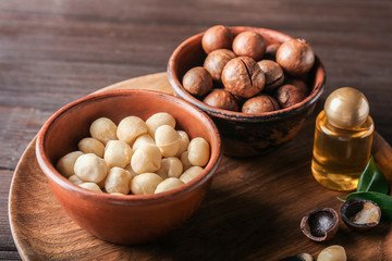 Bowls with macadamia nuts and oil on wooden plate