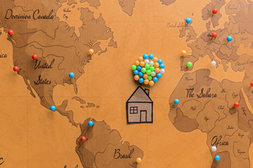 Paper house with pins on world map