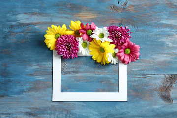 Frame with beautiful flowers on wooden background