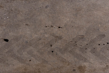 Tire tread mark on dirty asphalt, closeup background and texture