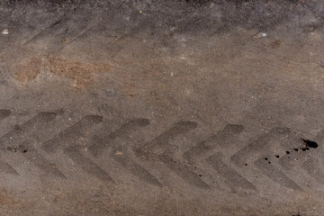 Tire tread mark on dirty asphalt, closeup background and texture