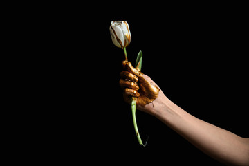 Painted hand with tulip flower against dark background