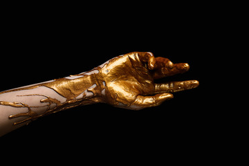 Female hand with golden paint against dark background