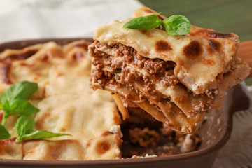 Taking of piece of tasty lasagna from casserole, closeup