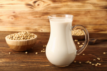 Jug of tasty soy milk on wooden table