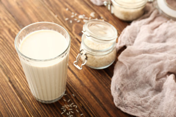 Glass of tasty rice milk on wooden table