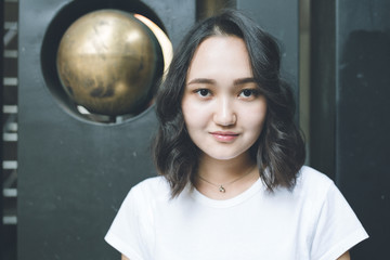 Naklejka premium Optimistic asian girl in a white t-shirt, urban portrat