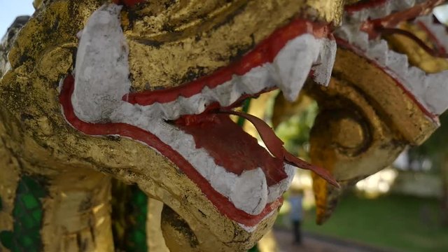 Close up of a golden dragon head outside of a famous temple of Luang Prabang in Laos during a sunny day